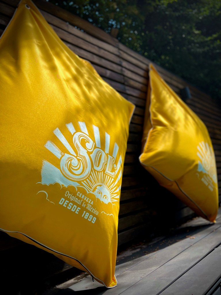 Cojines Köff amarillos con el logo de cerveza Sol serigrafiado, en una terraza