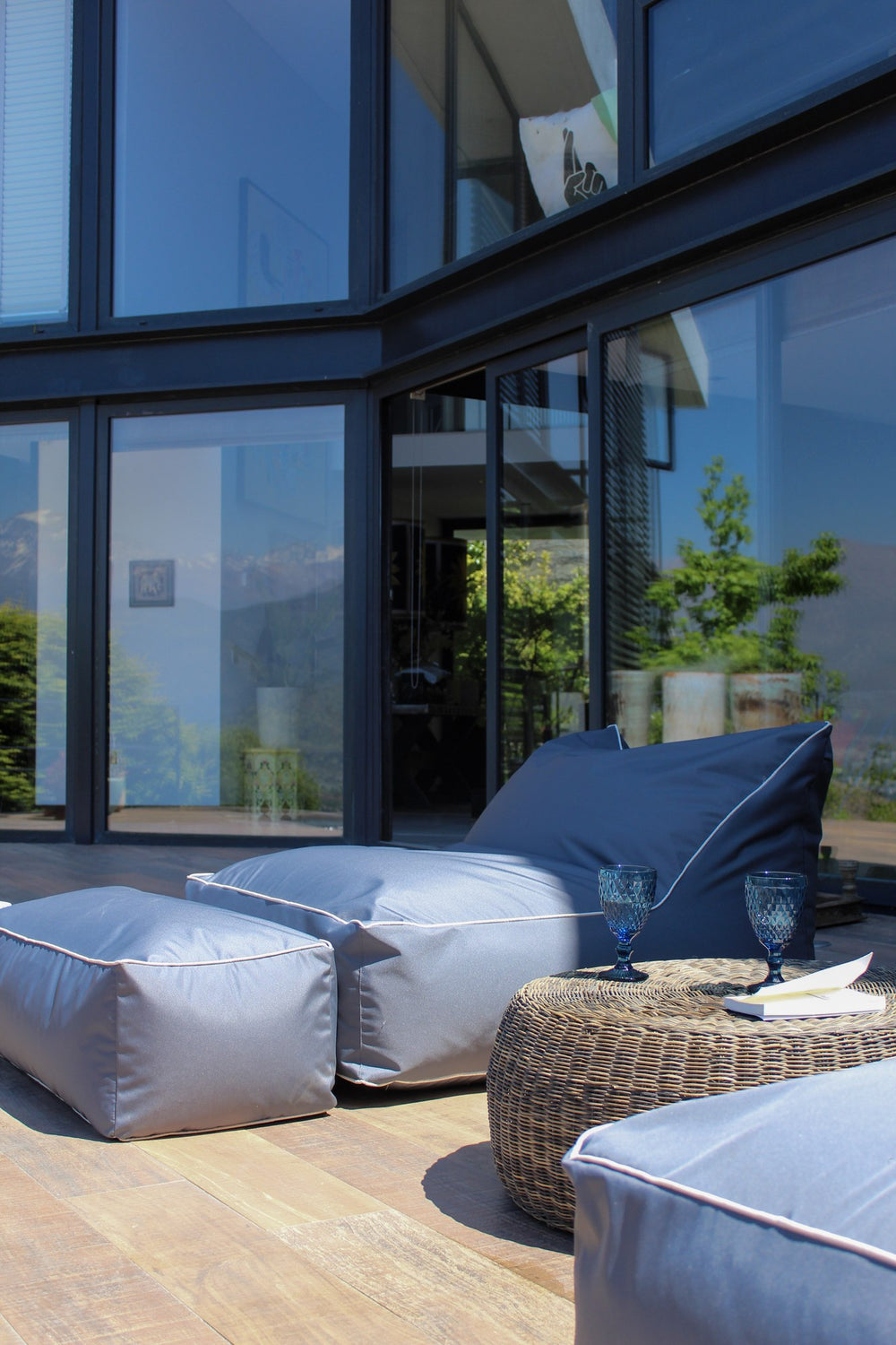 Reposera y modular Köff en la terraza de una casa de vidrio, con la cordillera reflejada